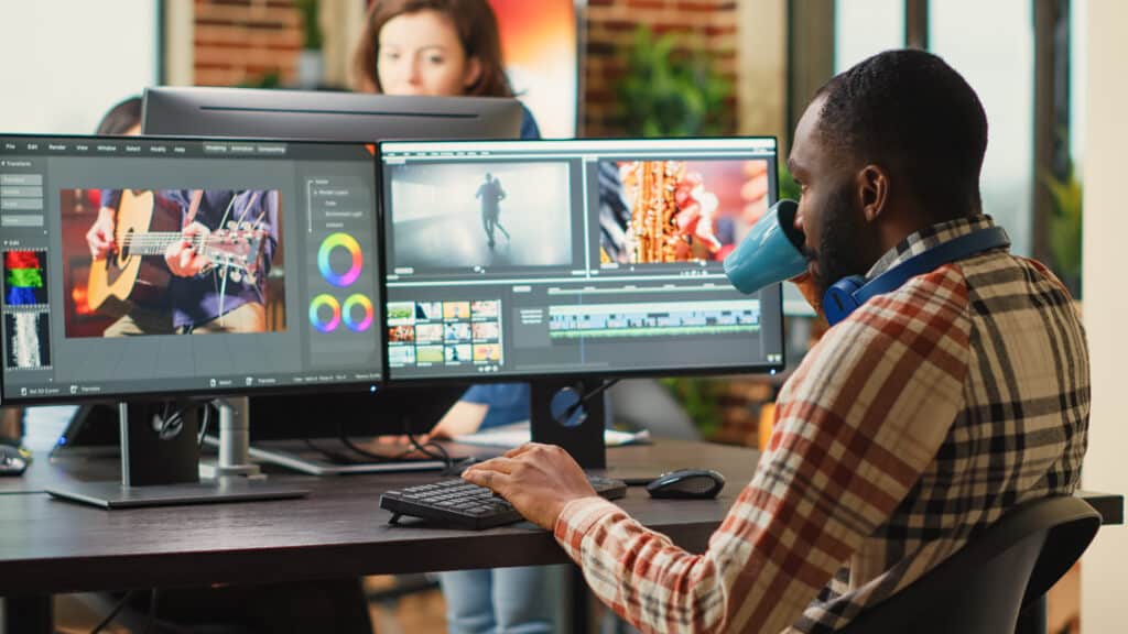 This comprehensive guide breaks down the key elements of an optimized web page to create the ideal user experience. Learn how to optimize for speed, mobile, SEO, navigation, content, multimedia, forms, and checkout. - The Anatomy of an Optimized Web Page: A Comprehensive Guide - a man sips coffee while working on a multi media presentation across two screens - your wp guy
